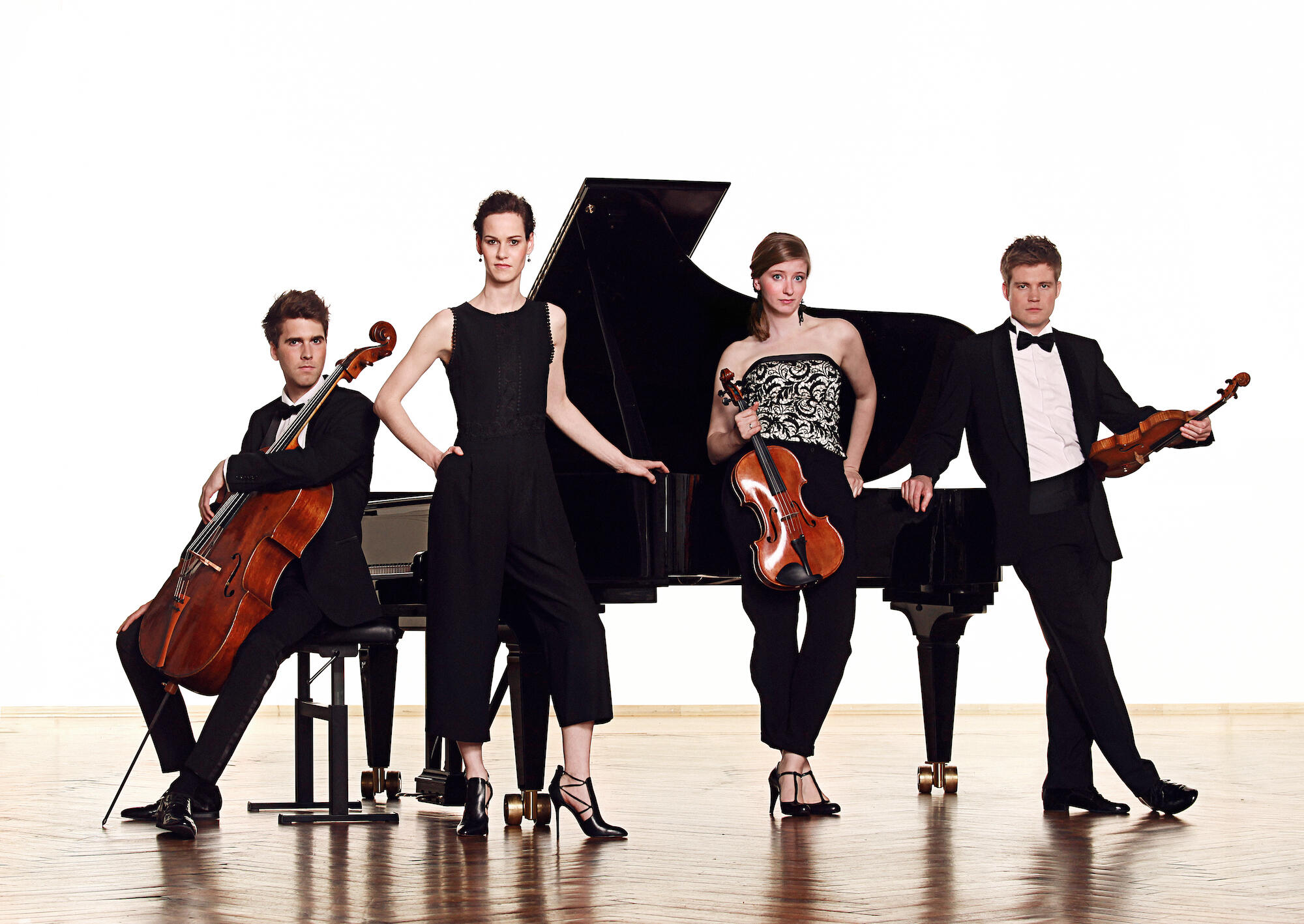The members of the Notos Quartet in front of a grand piano, holding instruments