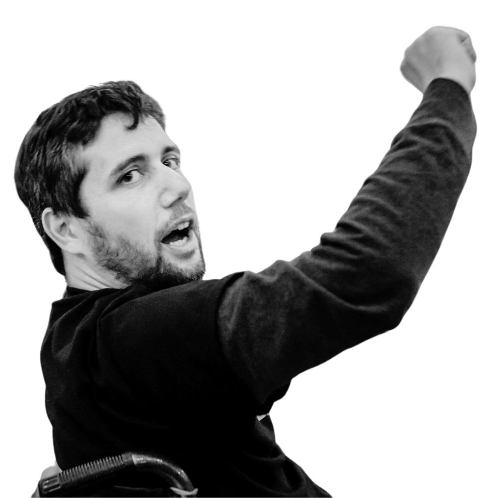 Image of Ady Barkan looking over his right shoulder with his right hand raised in a fist.