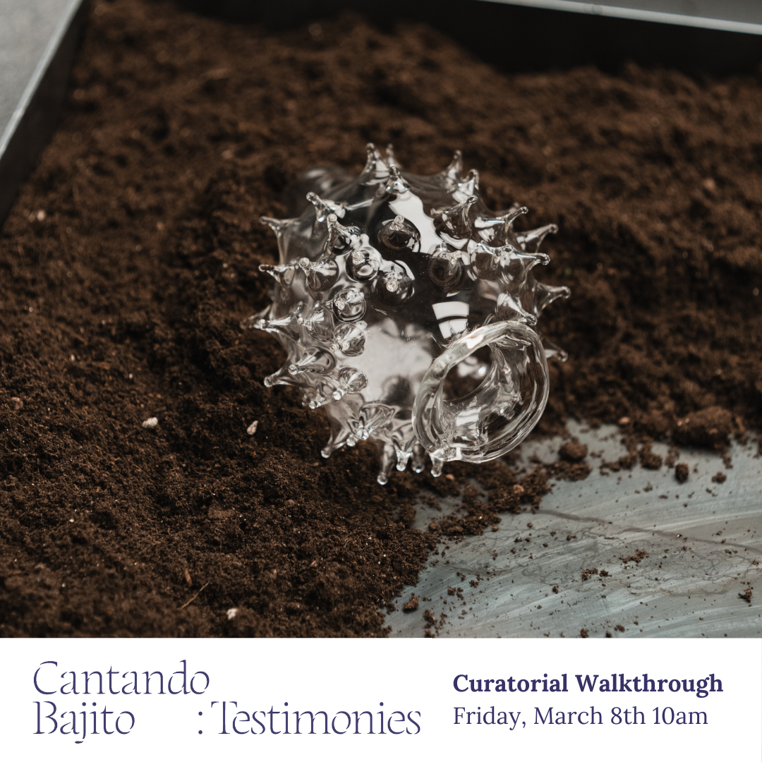 Glass vessel with prongs resting in a basin filled with dirt. Some dirt has been swept aside, revealing the metal bottom of the basin.