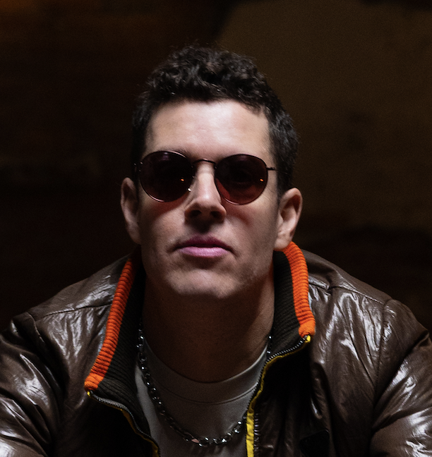 Juan Losada is a Caucasian man with dark hair. He is wearing sunglasses and a brown leather coat