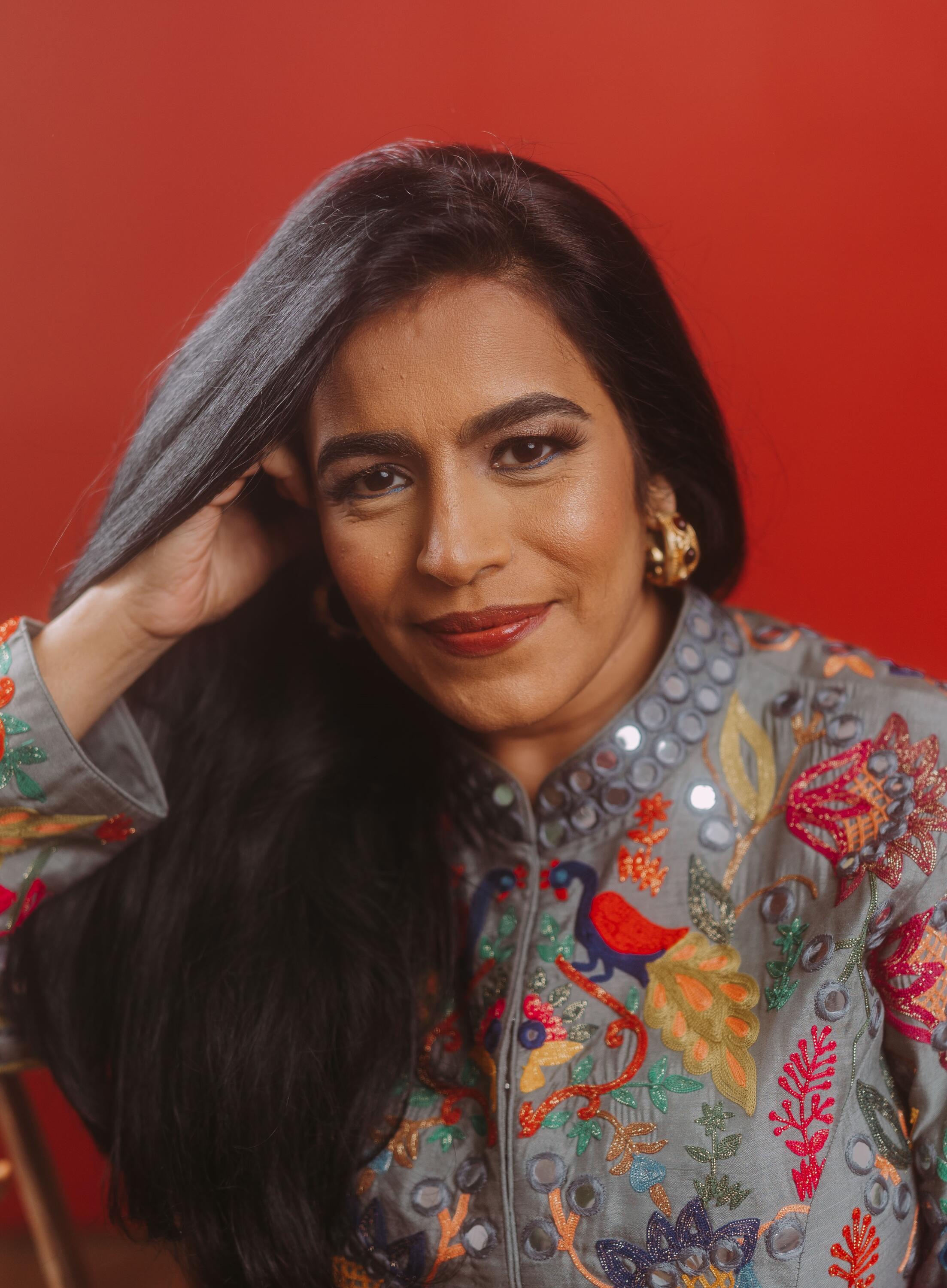 Falu is an indian woman with long dark hair. She is wearing a patterned sari.