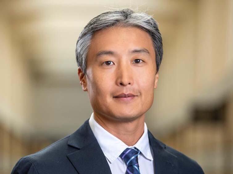 Head shot of a grey-haired Asian man in a suit and tie.