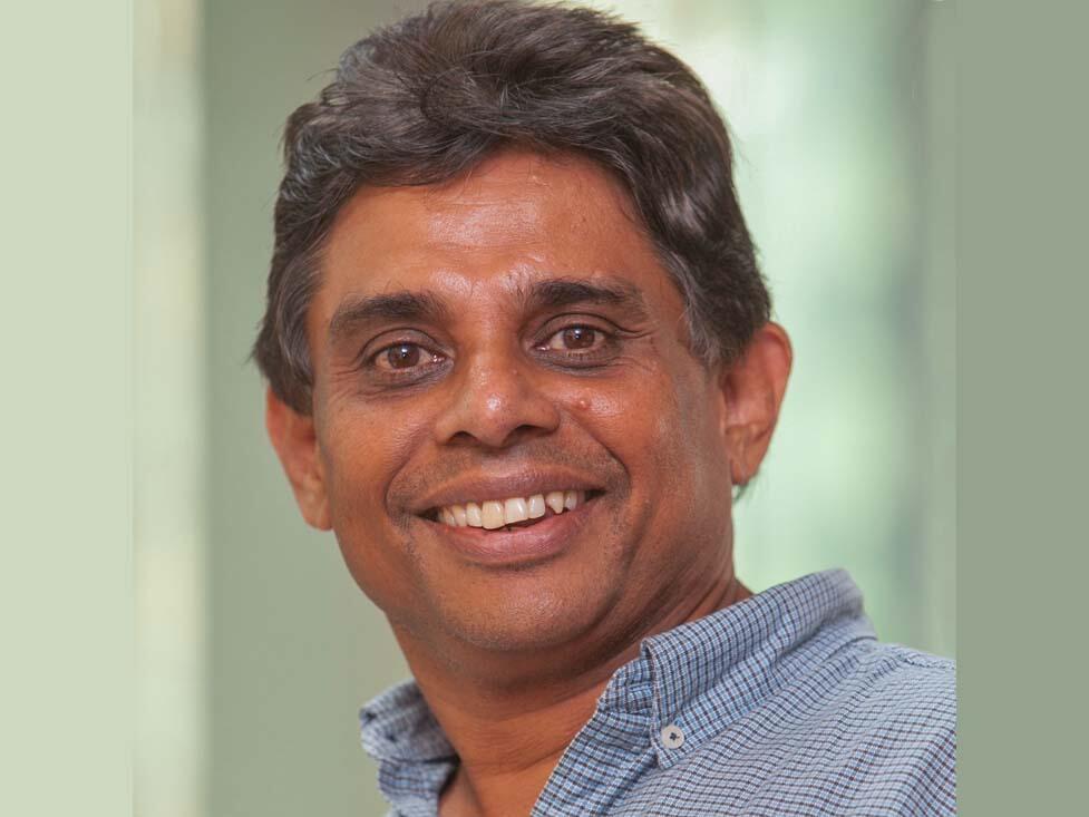 Headshot of a smiling black- and grey-haired Indian man