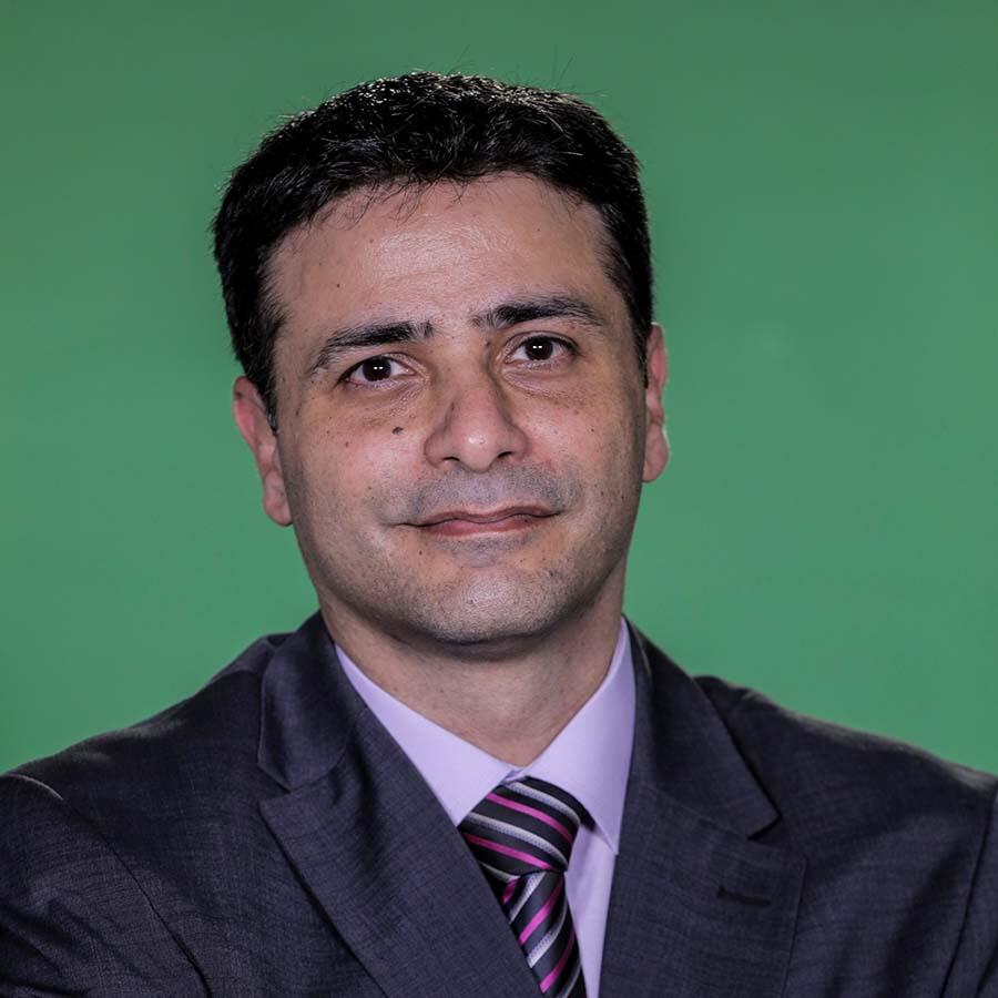 A dark-haired middle-aged man wearing a dress shirt, tie, and suitjacket