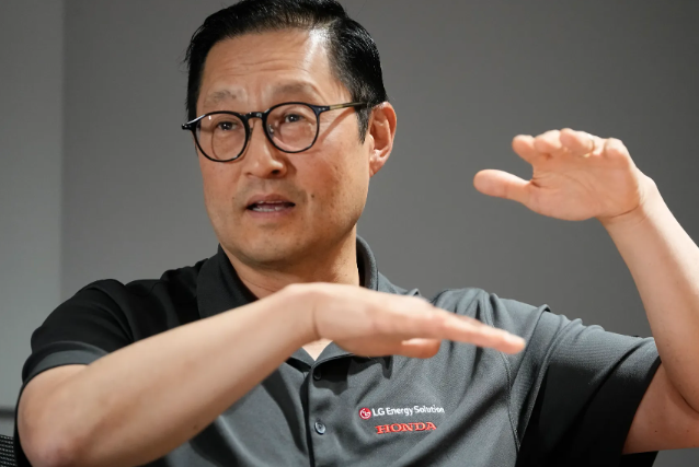 Asian man in glasses gesturing while giving a presentation