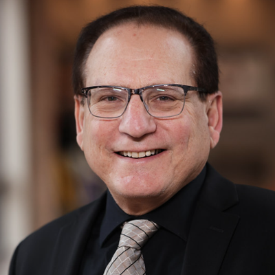 Smiling man with glasses wearing dark suit, silver tie