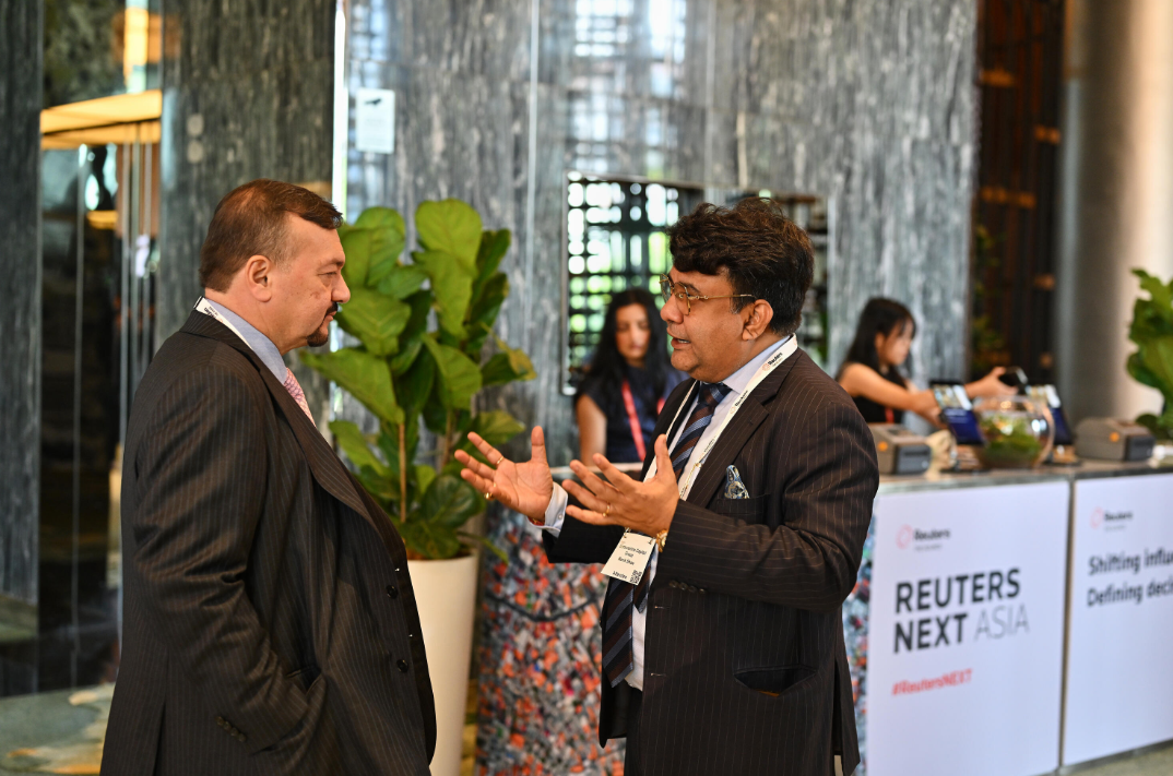 Attendees network at Reuters NEXT Asia in a modern event space with branded signage.