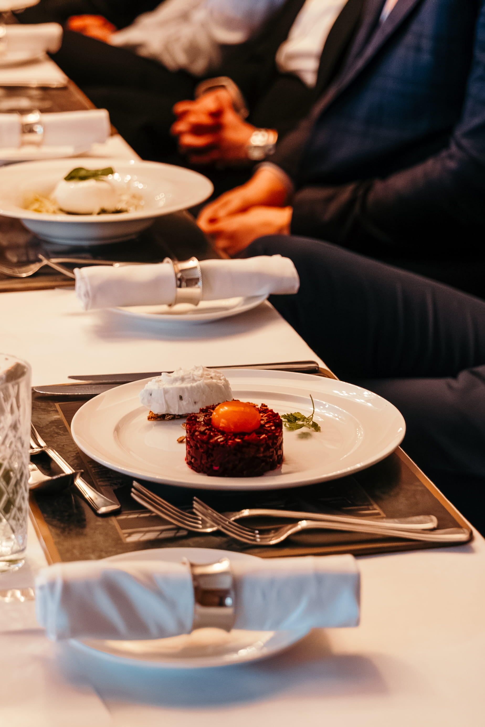 Plated food and table settings prepared for attendees at a Reuters NEXT dining event.
