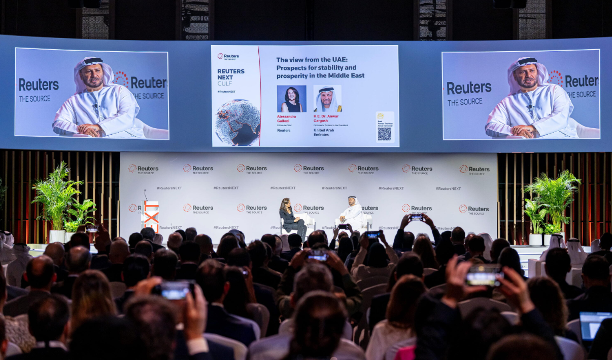 H.E. Dr. Anwar Gargash speaks on stage at Reuters NEXT Gulf before a large audience.