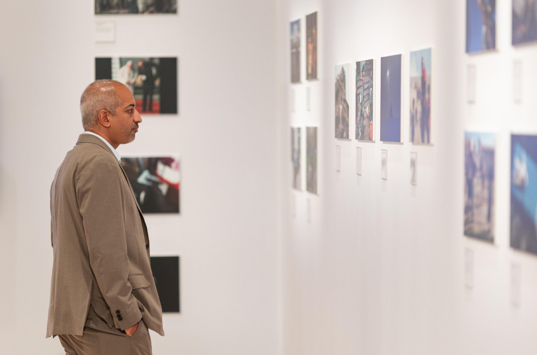 Attendee views a Reuters photo gallery displayed on a white exhibition wall.