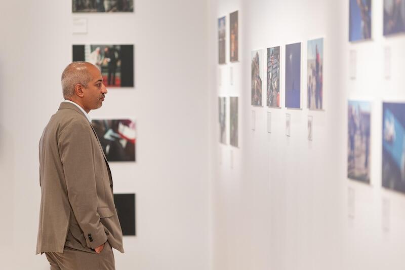 man viewing framed photos in a gallery hallway.