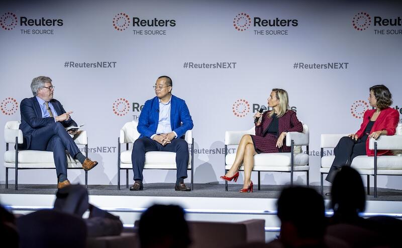 four speakers seated onstage, Reuters/"#ReutersNEXT" backdrop.