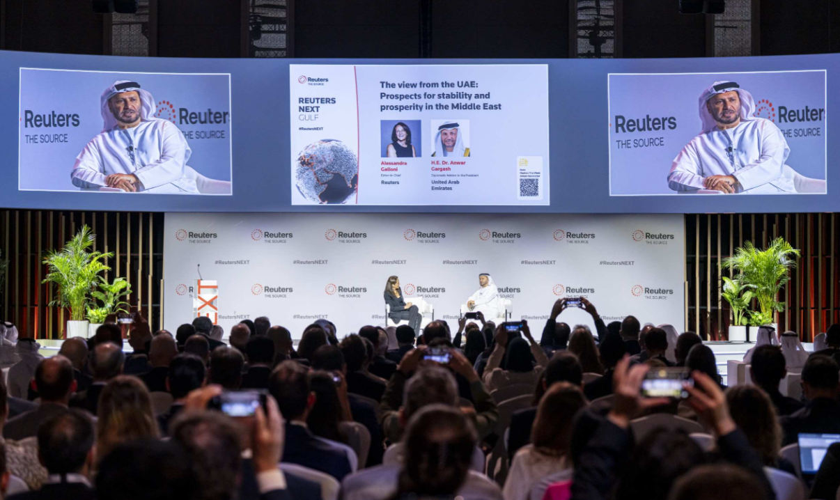 A packed audience watches a Reuters NEXT Gulf panel on the UAE's prospects for stability and prosperity in the Middle East, with several attendees photographing the speakers on their phones.