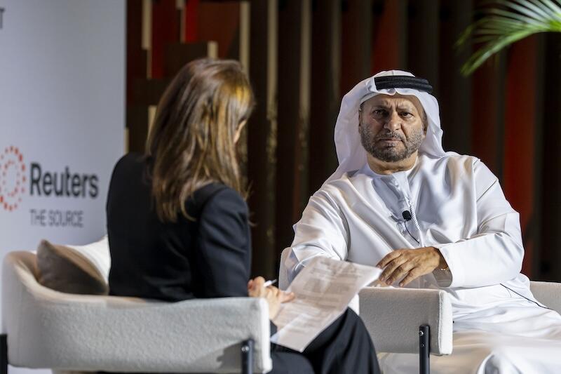 A seated conversation onstage between a woman (back to camera) and a man wearing a white robe and headscarf; Reuters branding is visible in the background.