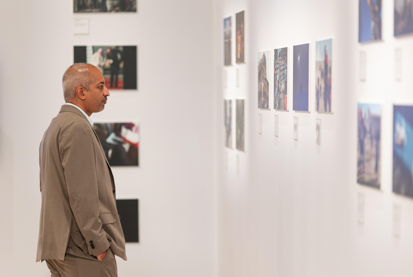 man viewing framed photos in a gallery hallway.