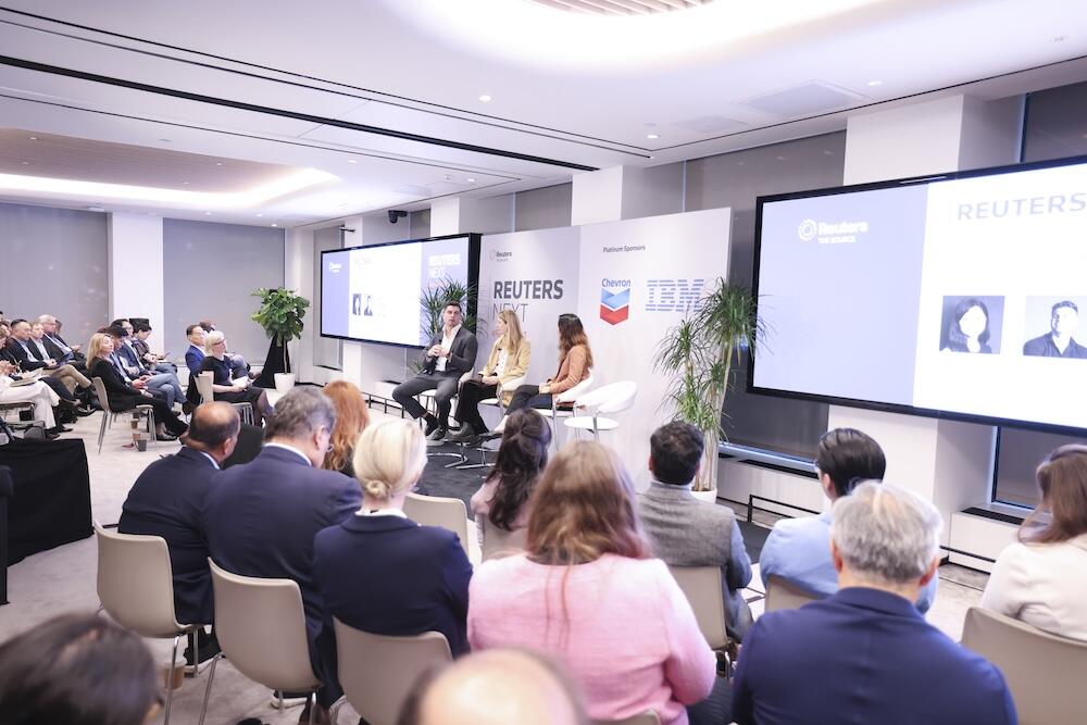 Panel discussion with speakers on stage and audience seated at Reuters NEXT.