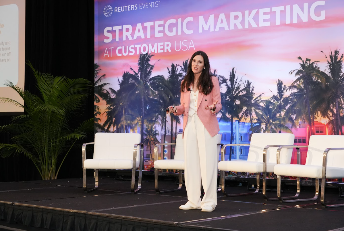 Speaker presenting on stage with “Strategic Marketing” backdrop, engaging the audience with a hands‑on talk