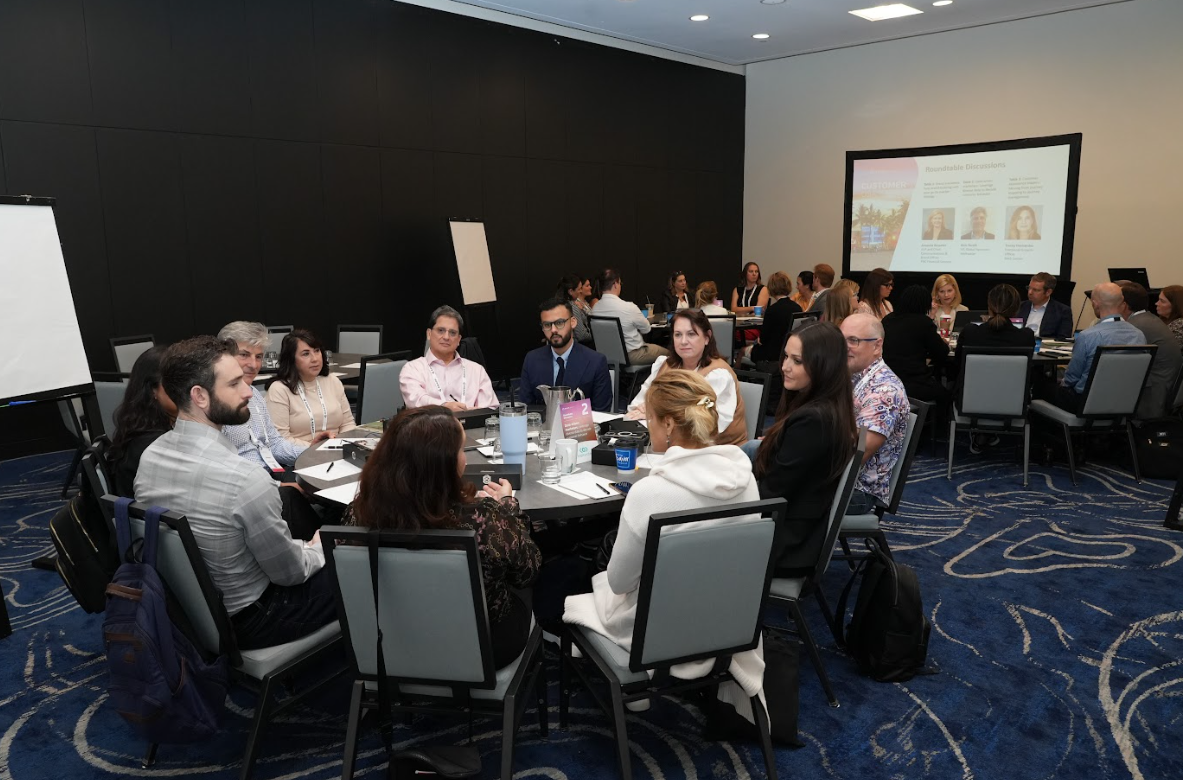 Room full of roundtable groups debating topics, sharing notes, and collaborating during a breakout