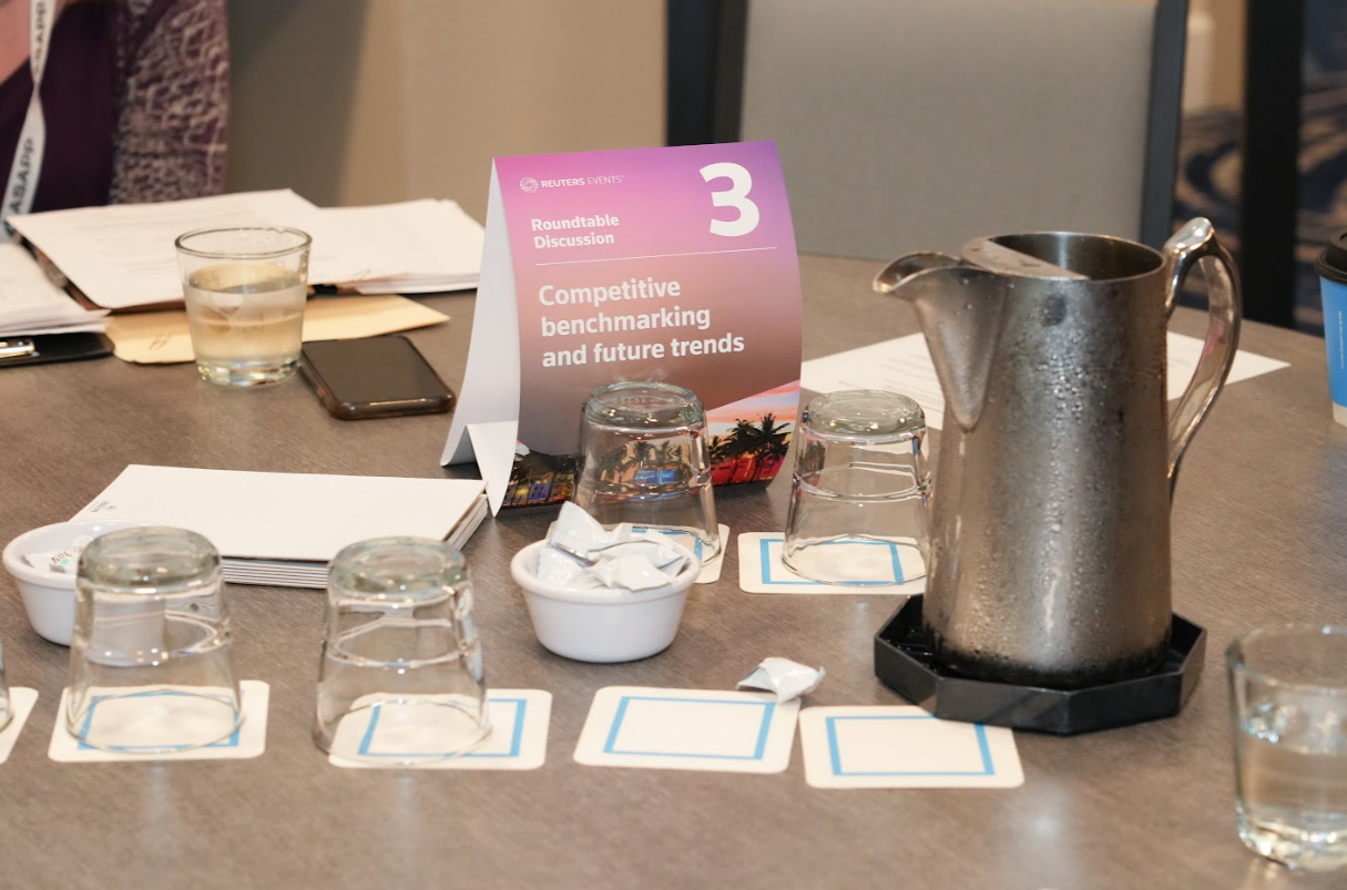 Table setup with “Roundtable Discussion: Competitive benchmarking and future trends” sign, notepads, and water glasses ready for interactive work