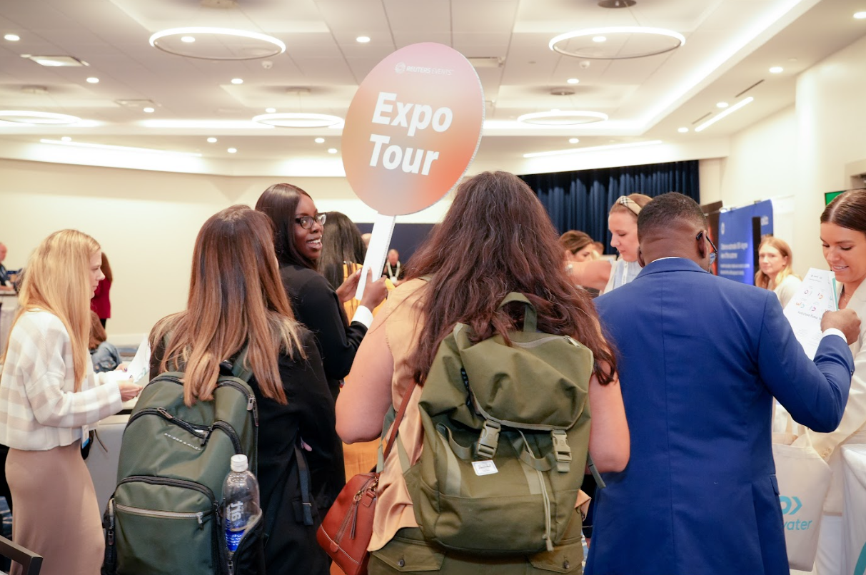 Group following an “Expo Tour” sign, stopping at booths for interactive demos
