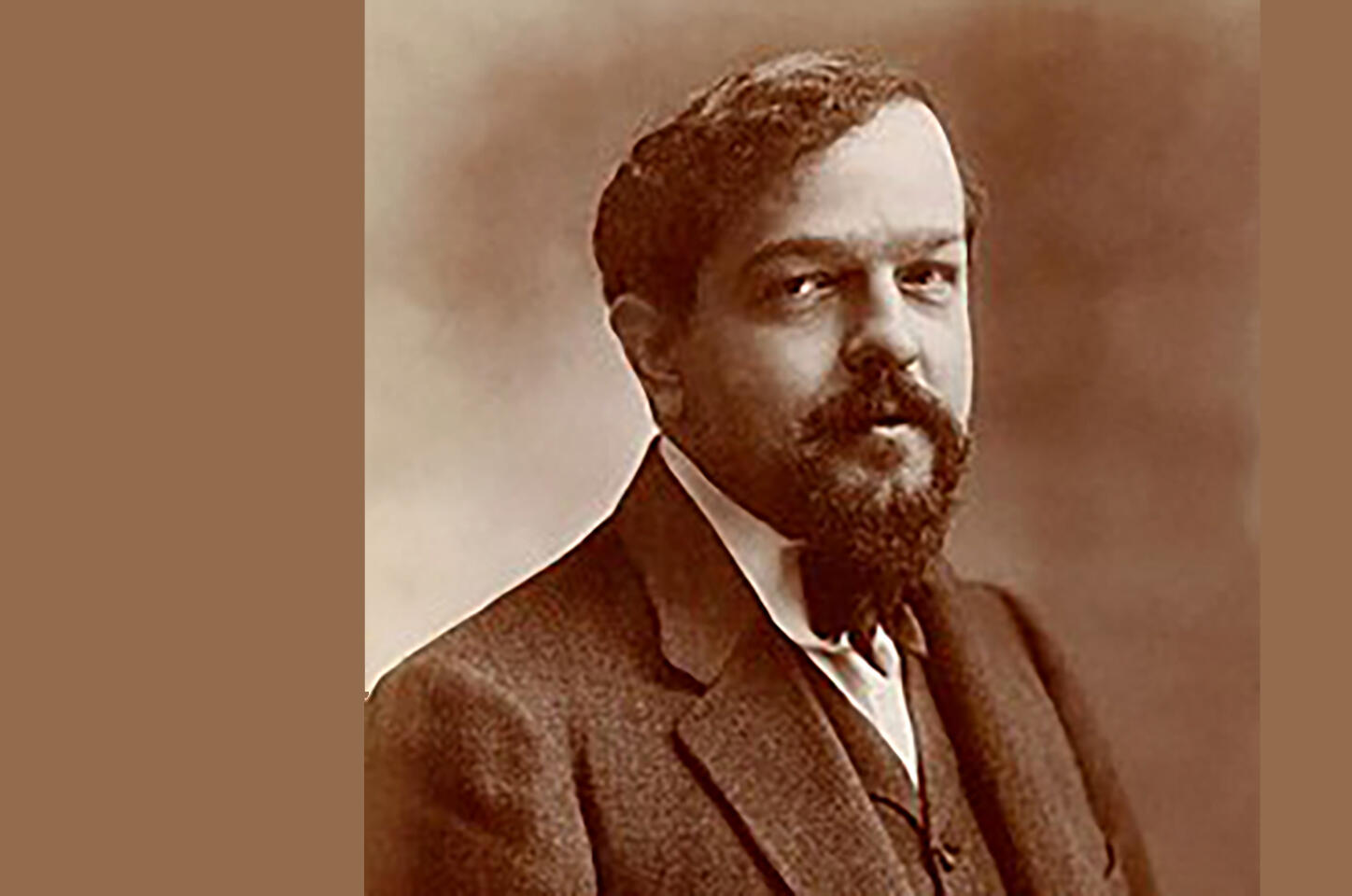 Sepia tone photo of Claude Debussy. Middle-aged white man with  goatee, mustache, side-combed hair, wearing late 19th century suit and tie