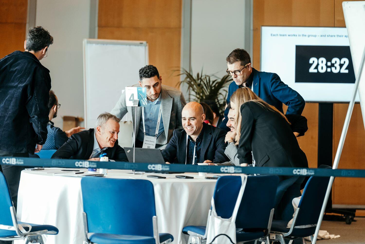 Group gathered around a table solving a problem on a laptop