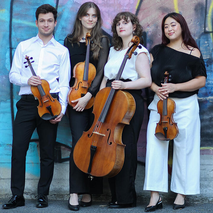Wearing black and white, members of the Katarina Quartet stand in front of a colorfully painted wall holding instruments. Left to right: young white man, two young white women, one young Asian woman. 