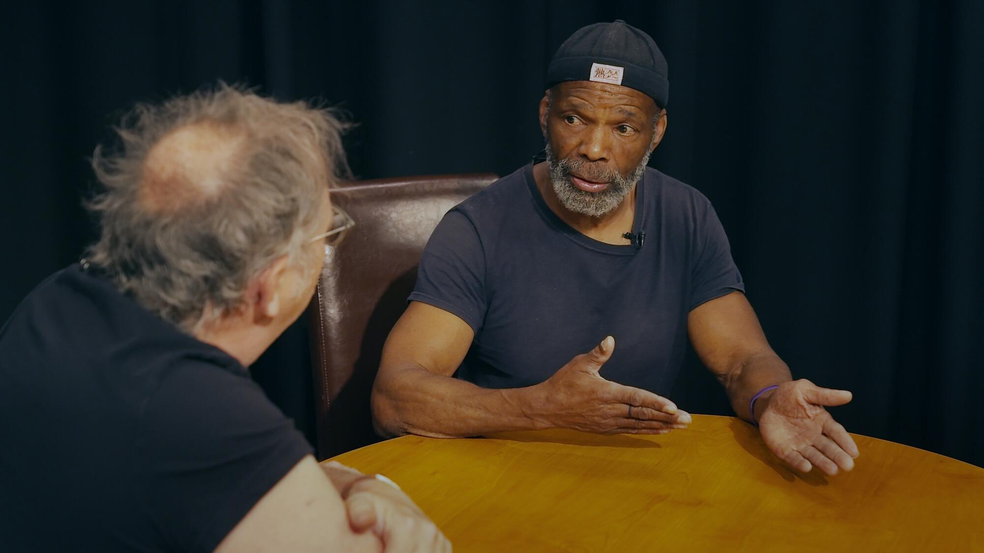 Two men seated at a table having a discussion.