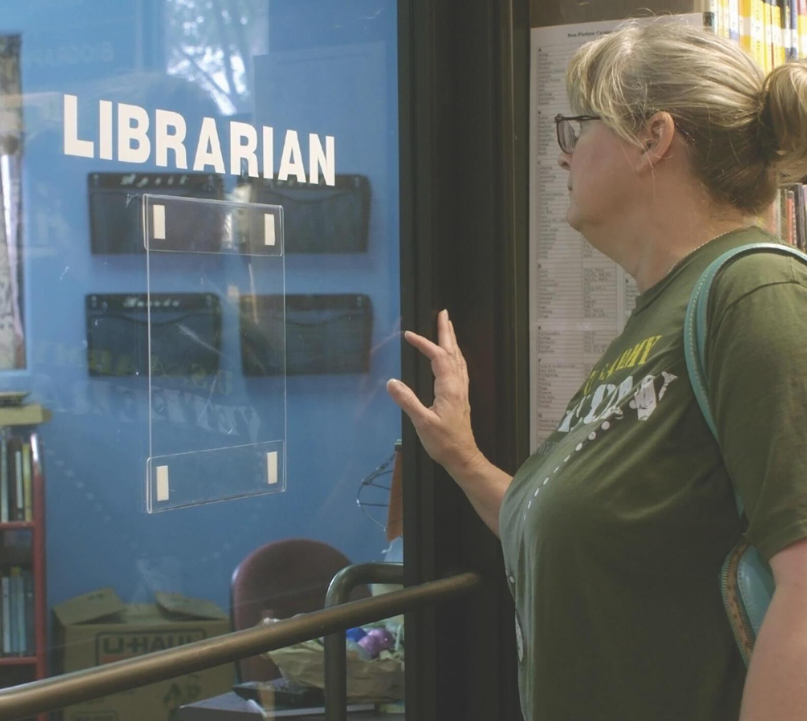 Woman pushing open a glass door labelled "LIBRARIAN."