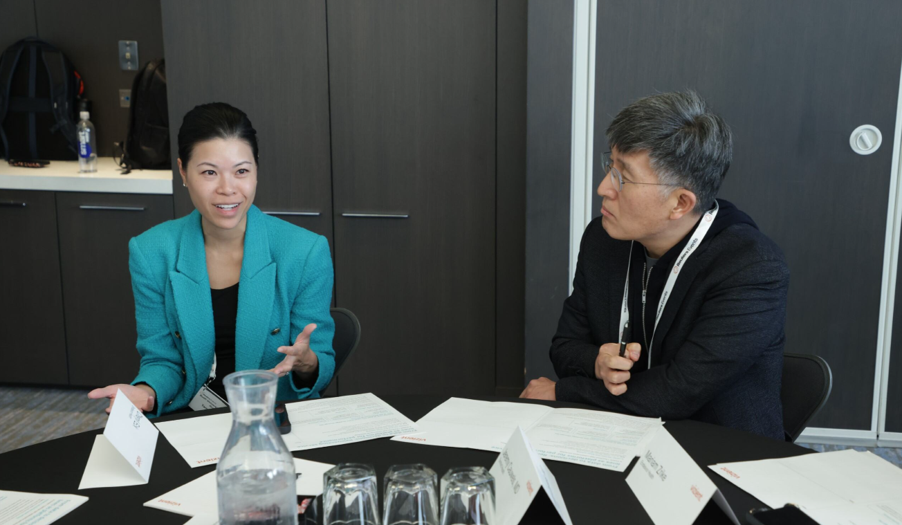 Two conference attendees engaged in discussion at a roundtable session at the Total Health conference, with name cards and documents on the table.