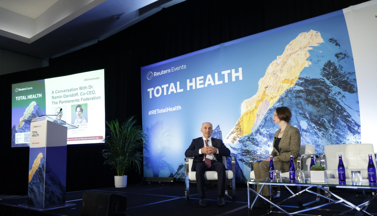 Dr. Ramin Davidoff, Co-CEO of The Permanente Federation, in conversation with an interviewer on stage at the Reuters Events Total Health conference, with the #RETotalHealth backdrop and branded podium visible.