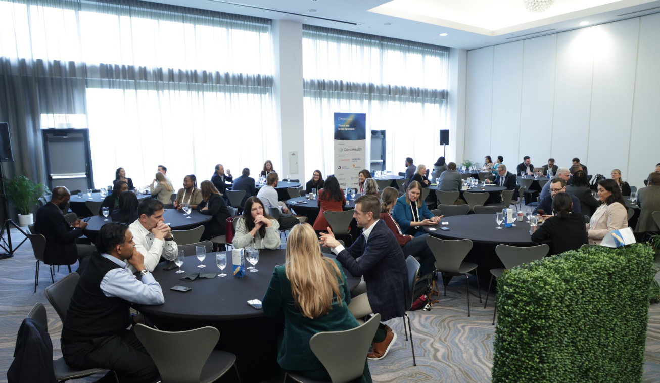 Attendees networking at round tables during a session at the Total Health conference, with a sponsors banner visible in the background.
