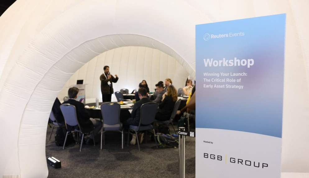 Workshop inside a white inflatable room; a presenter addresses seated participants beside a sign reading "Reuters Events Workshop… Winning Your Launch," hosted by BGB Group.