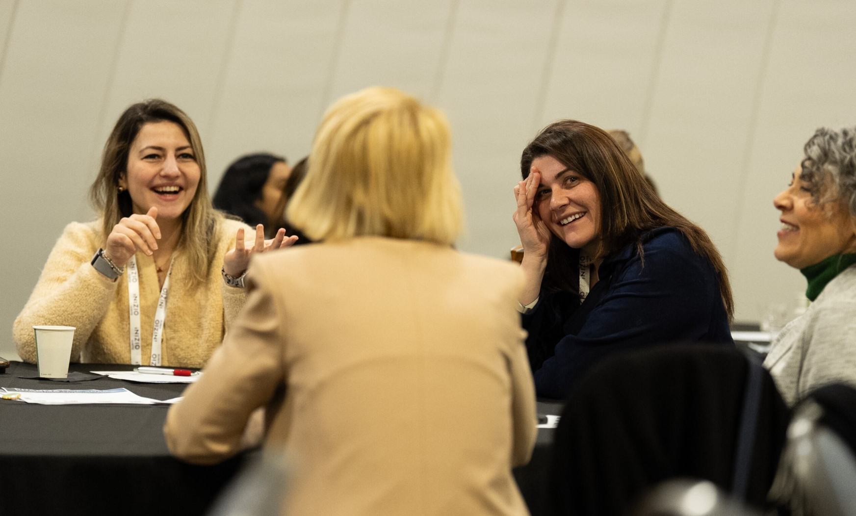 Attendees laughing and engaging in conversation at a roundtable session at an Inizio conference.