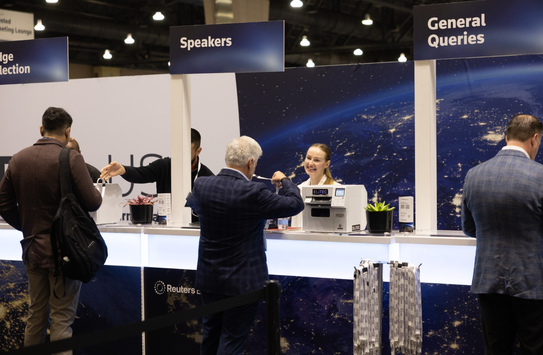 Reuters Events conference registration desk with Speakers and General Queries counters, staff assisting attendees.