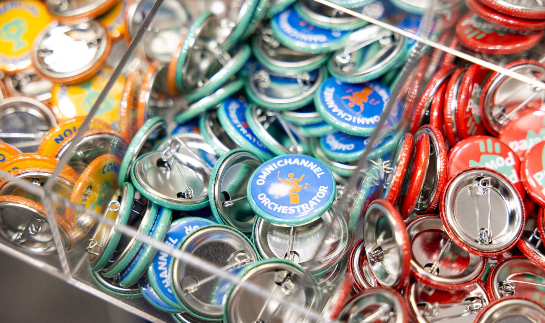 Branded pin buttons on display at a pharma conference, including "Omnichannel Orchestrator" and other pharma role-themed designs.
