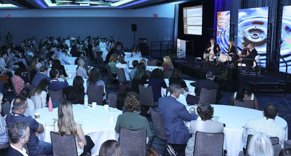 Audience at round tables listens to a panel discussion on stage at the Responsible Business USA 2025 conference.