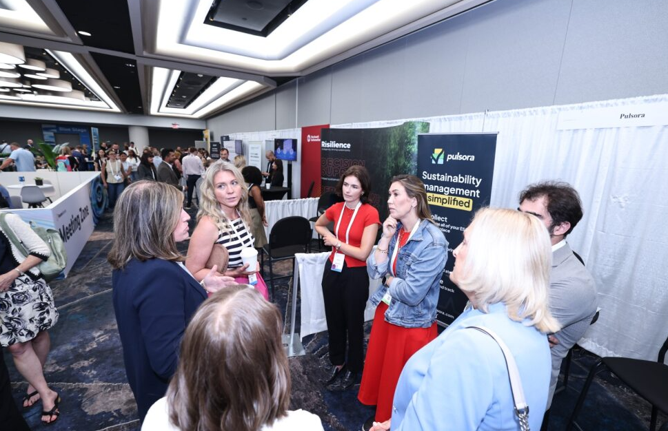 Small group in lively conversation on the expo floor, continuing discussion from a session