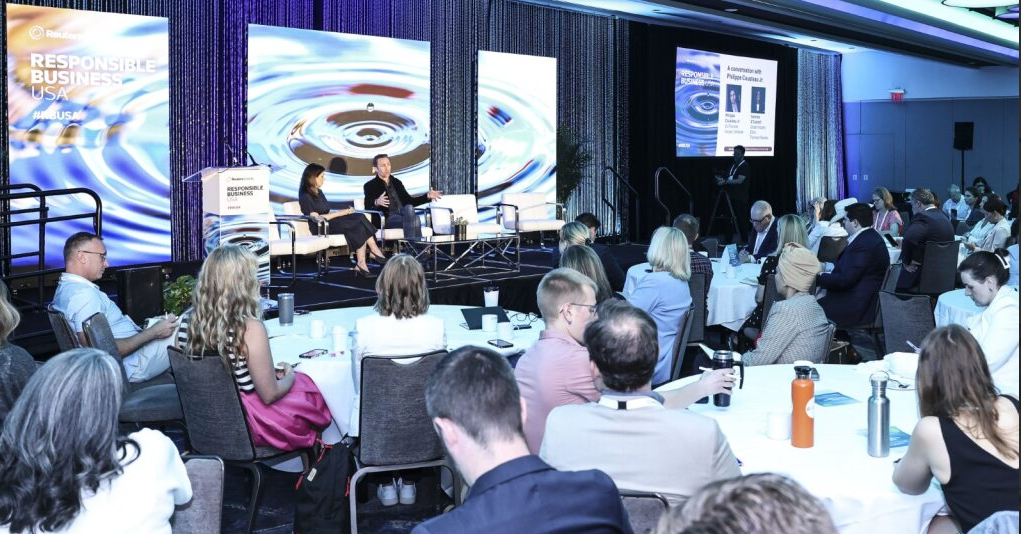 Wide shot of a panel at Responsible Business USA 2025, two speakers on stage, audience seated at round tables.