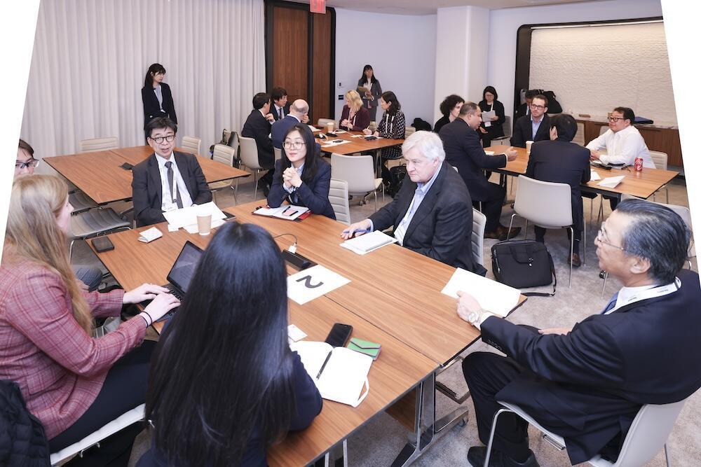 Photo of people at table in groups having a discussion.