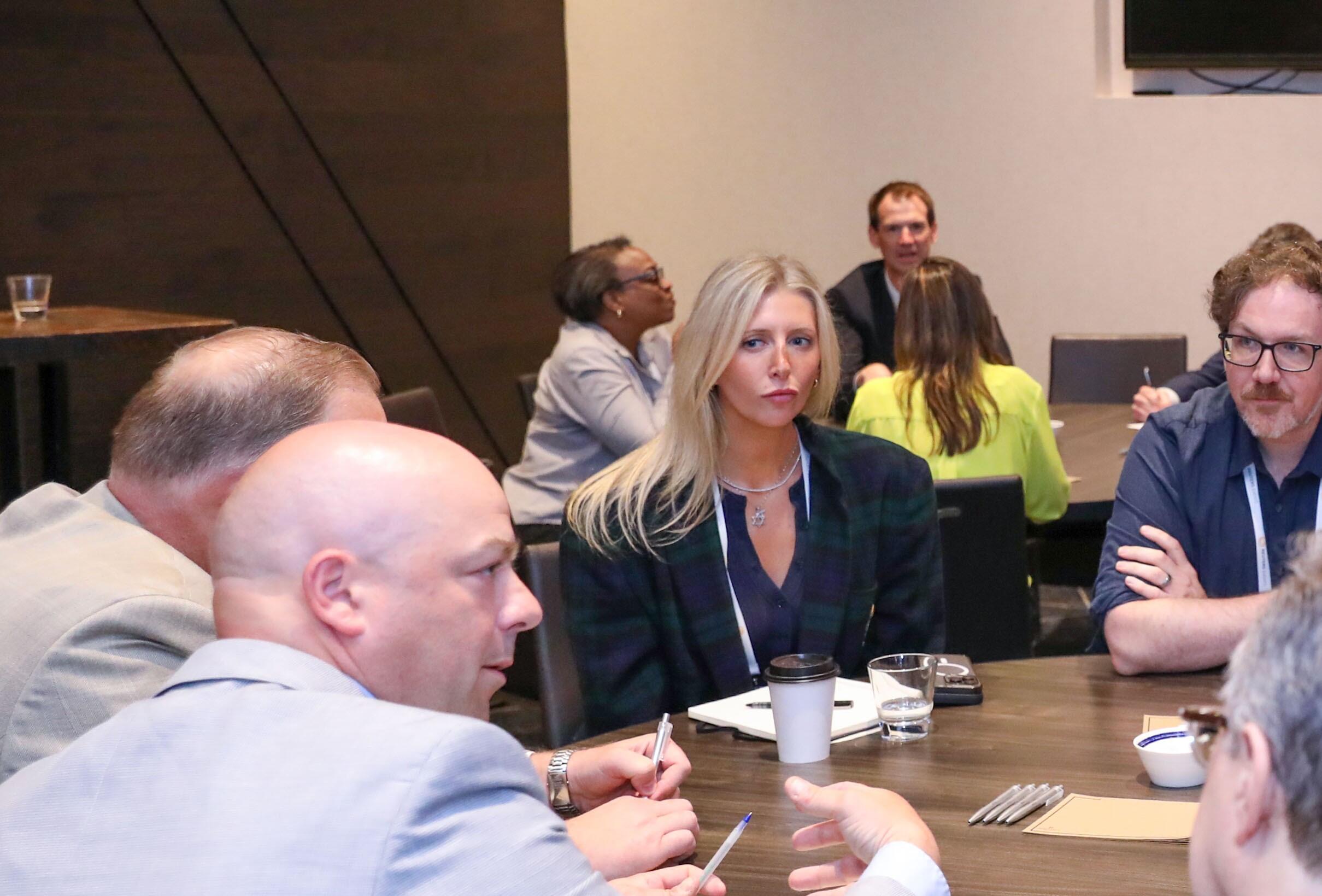 Several attendees listening attentively and discussing around a round table at a digital health conference.