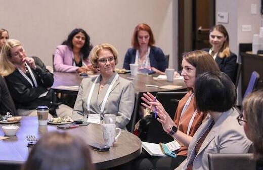 A large group of professionals seated at an extended table, focused on a speaker or presentation at a digital health conference.