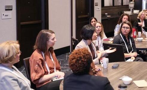 A group of attendees seated at a round table, engaged in conversation at a digital health conference.