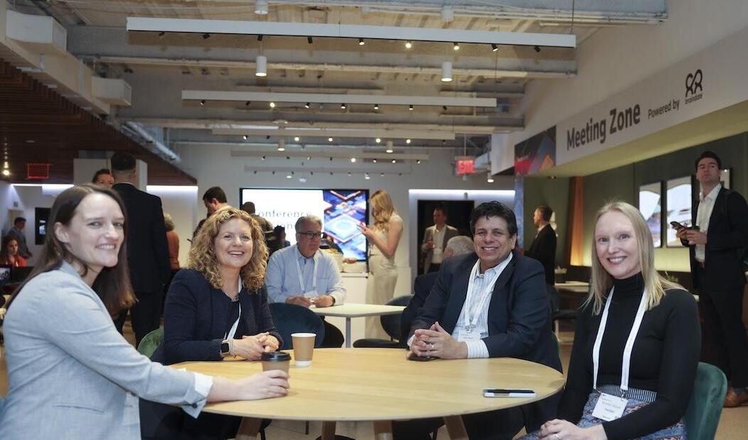 Four people posing for a photo at an event at a table