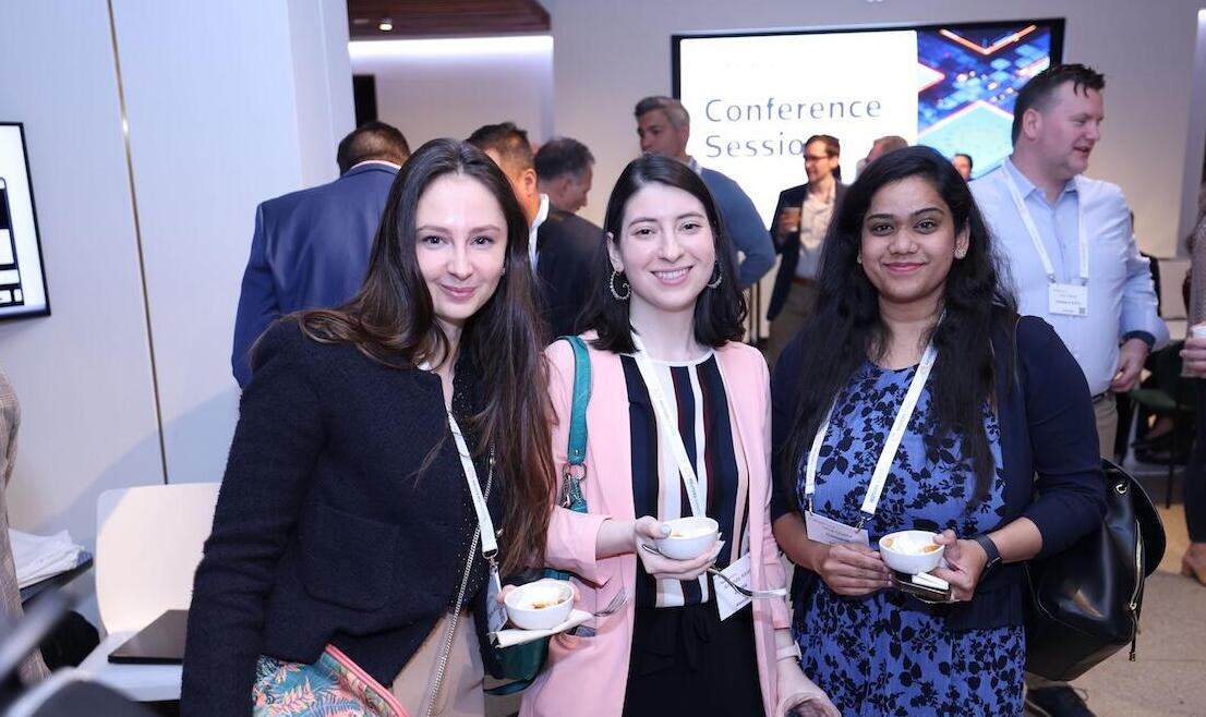 Three people posing for a photo at an event holiding tea cups
