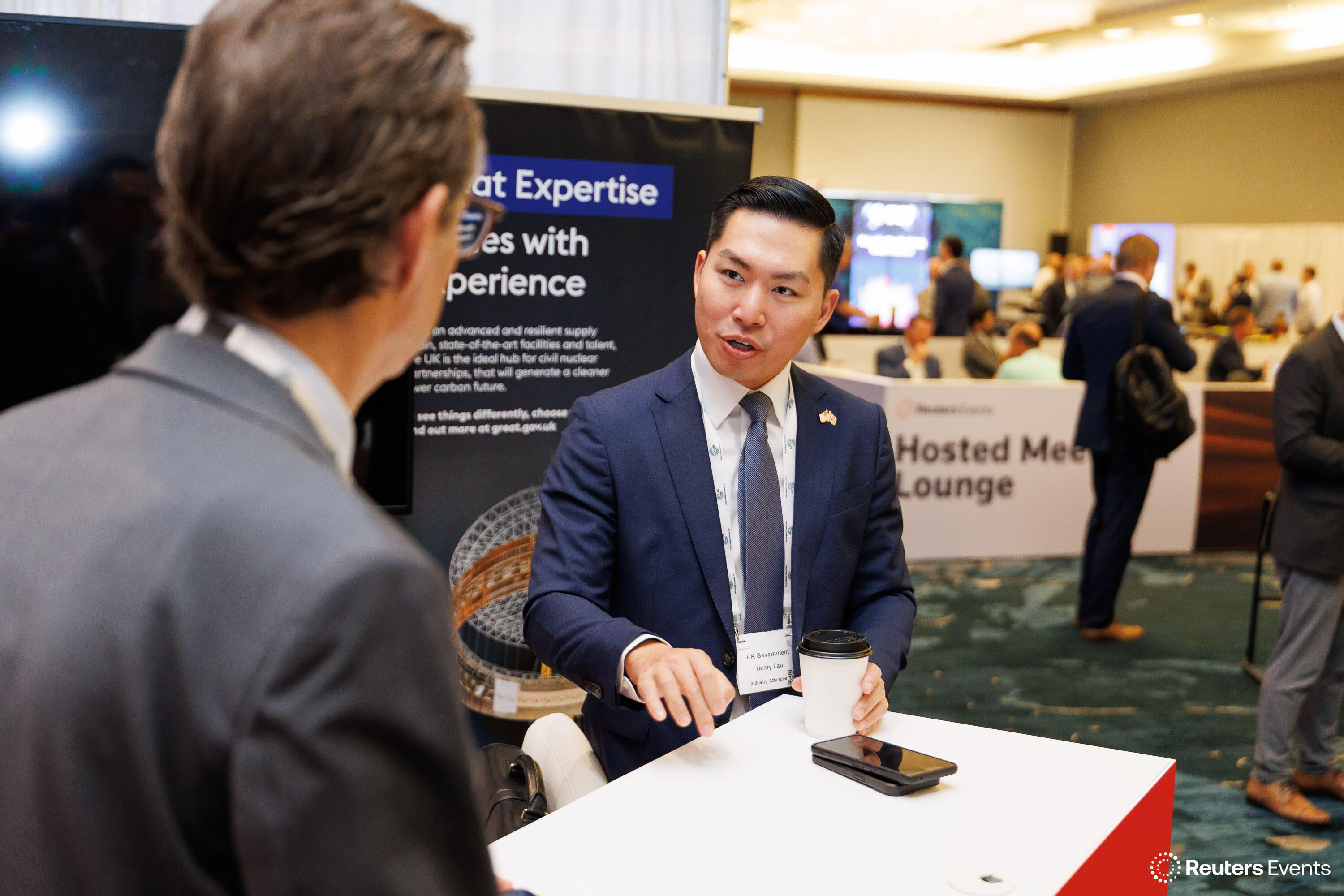 Two men in conversation at the UK Government exhibition booth on the conference floor