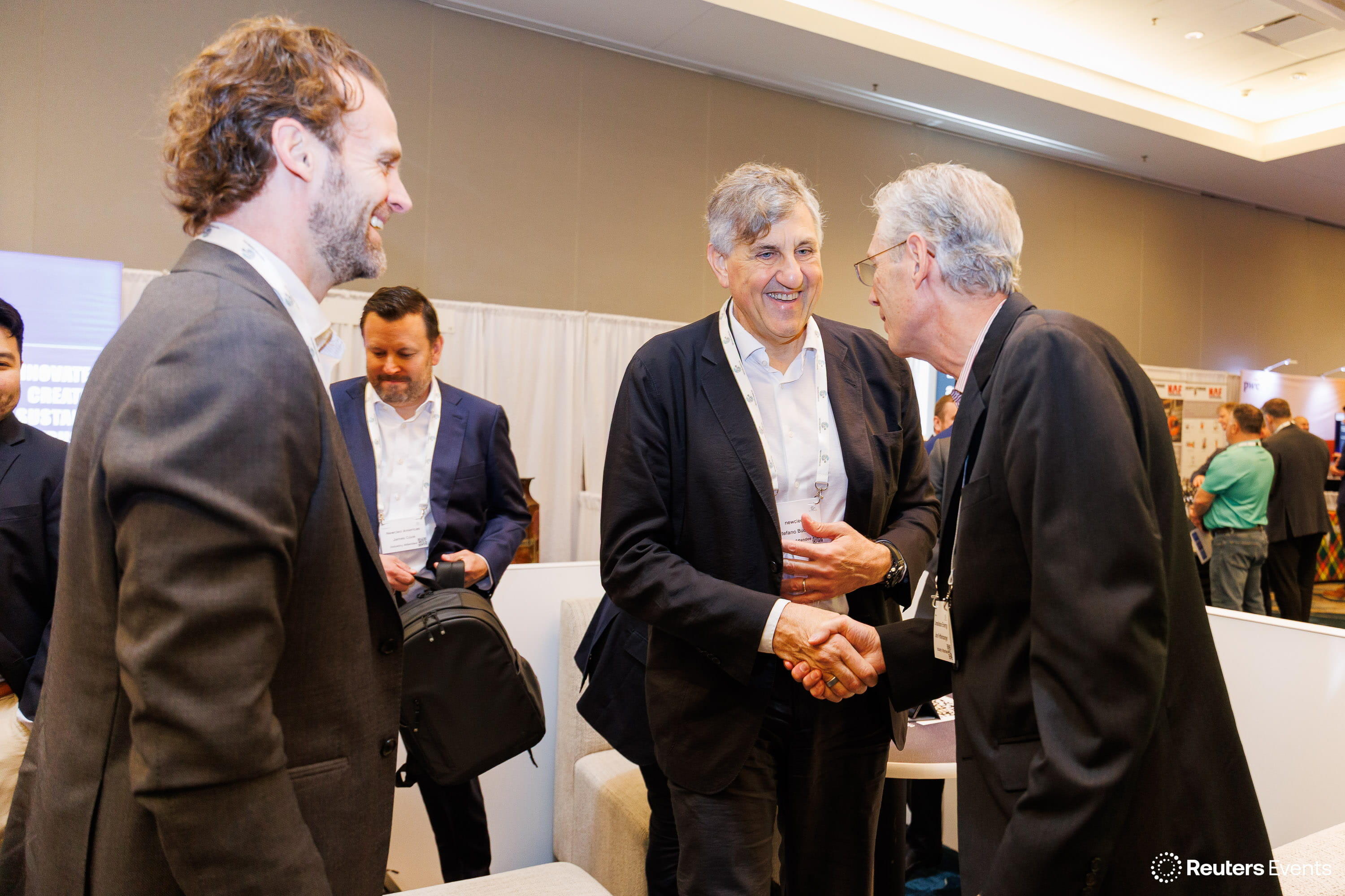 Two men shaking hands and smiling on the conference exhibition floor