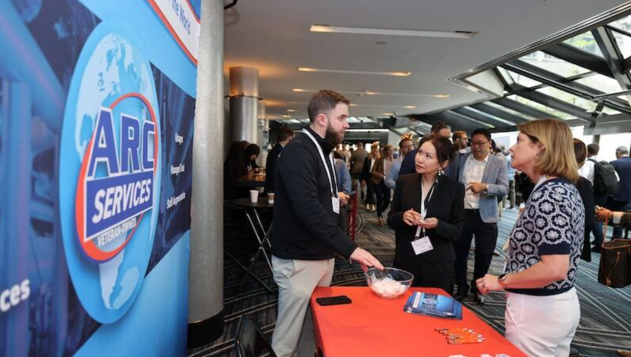 Attendees chat at the ARC Services exhibitor table in the SMR & Advanced Reactor conference expo hall.