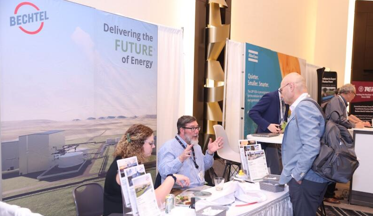 Bechtel booth reps meet with an attendee at the SMR & Advanced Reactor expo, with brochures and banner displays visible.