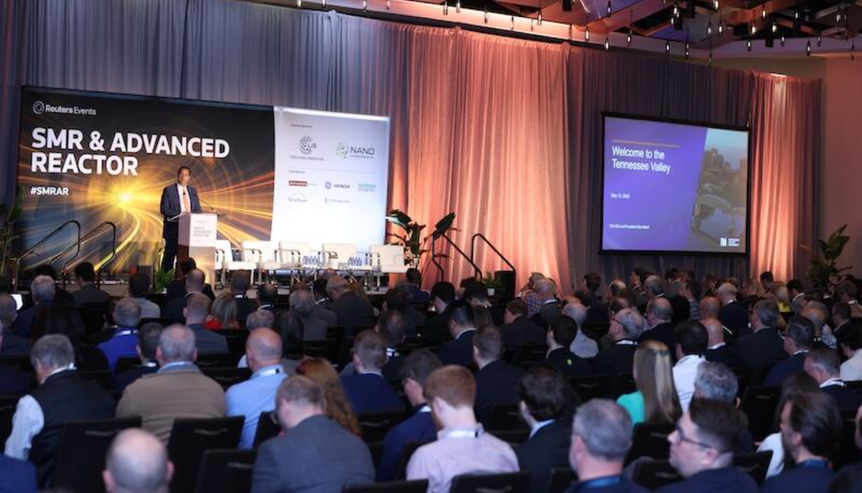 Keynote speaker addresses a full audience at the SMR & Advanced Reactor conference, with stage branding and slide visible.